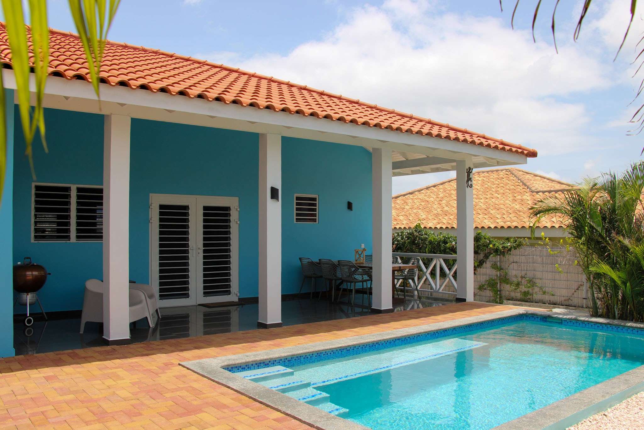 The villa seen from the pool with porch, barbecue and dining table
