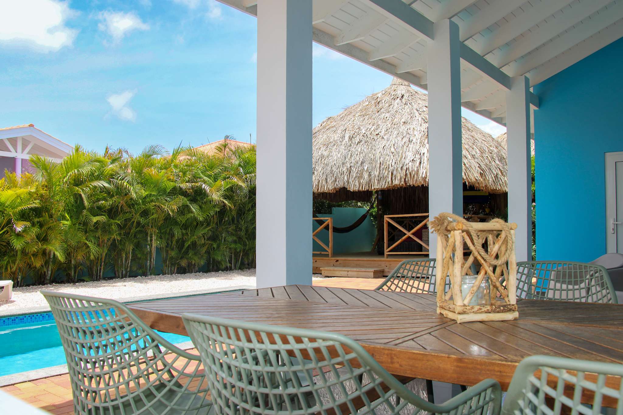 Dining table on the porch looking out over the pool and the palapa