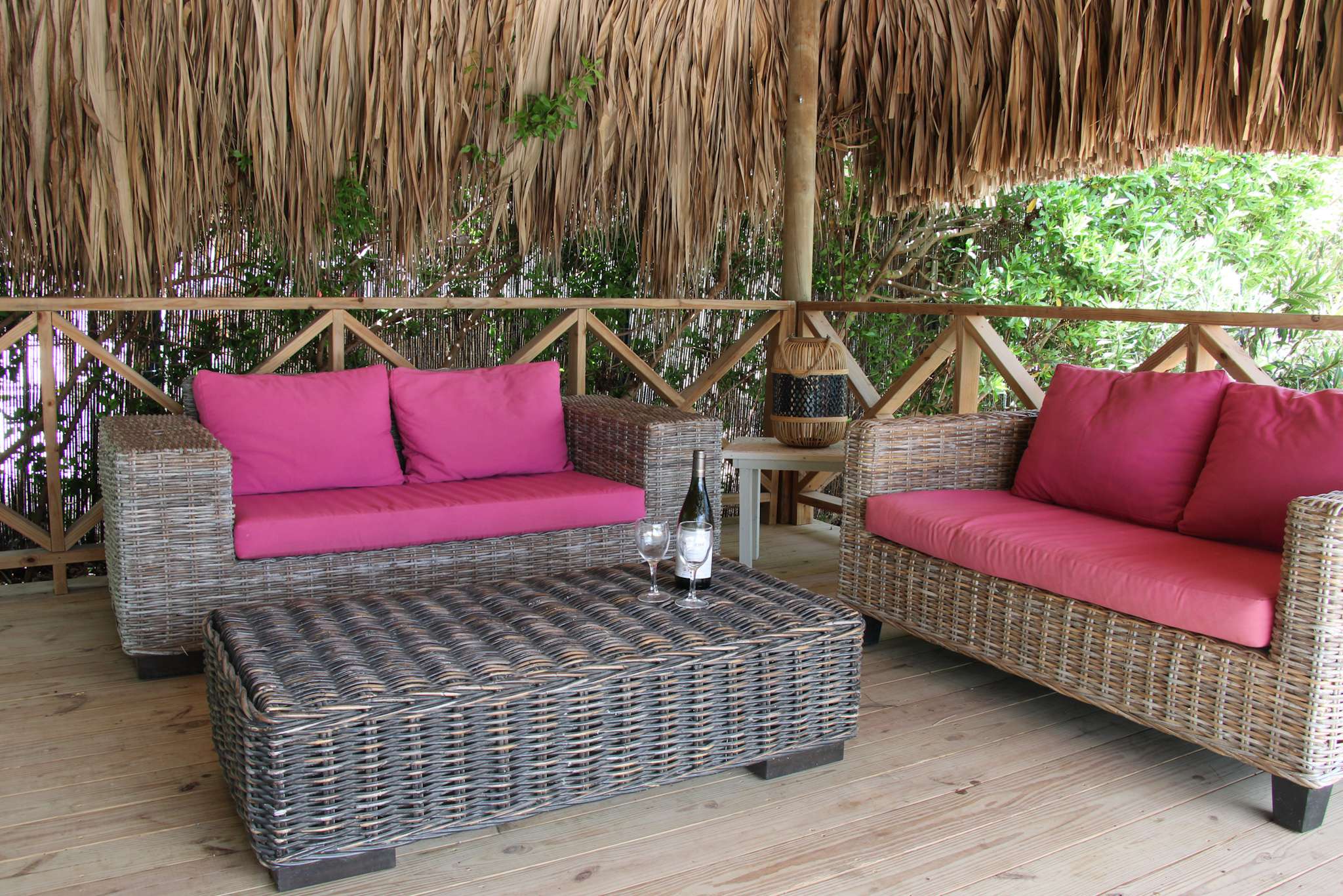 Lounge set with wicker sofas and pink cushions under the palapa
